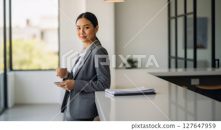 Thoughtful woman gazing out modern office window. 127647959