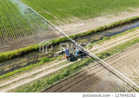 Autonomous machine is moving watering pivot along irrigation canal 127648282