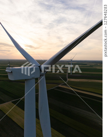 Aerial view of wind turbine on an agricultural filed at sunset. Close up of blades. 127648283