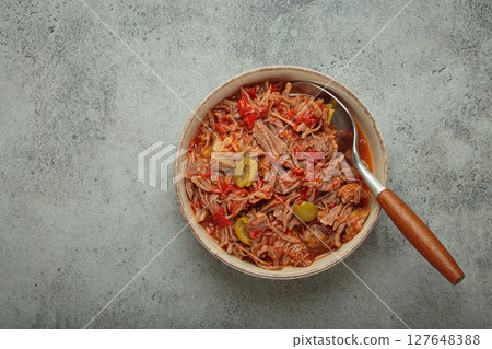Ropa vieja with white rice, tomato sauce and green olives on a plate top view, traditional dish of Cuba, space for text 127648388