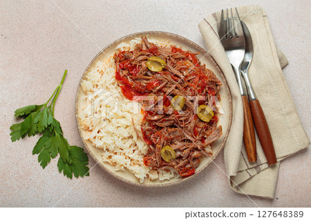 Ropa vieja with white rice, tomato sauce and green olives on a plate top view, traditional dish of Cuba Ropa vieja with white rice, tomato sauce and green olives on a plate top view, traditional dish of Cuba 127648389
