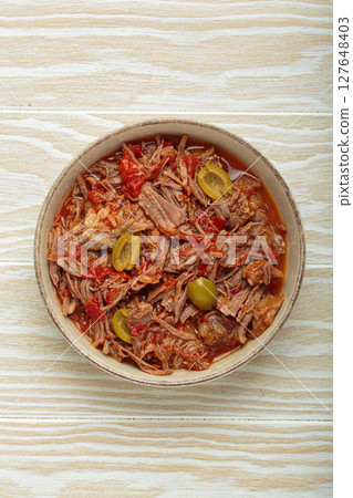 Ropa vieja with white rice, tomato sauce and green olives on a plate top view, traditional dish of Cuba 127648403