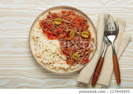 Ropa vieja with white rice, tomato sauce and green olives on a plate top view, traditional dish of Cuba 127648405