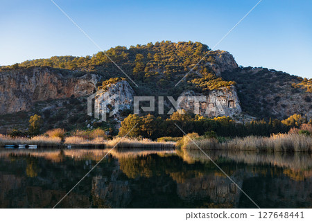 View of famous rock cut temples tombs of kings at ancient Greek city Kaunos in Caria or Caunus in Roman period in Anatolia. Popular place for family travel on summer vacation. Dalyan, Mugla Turkey View of famous rock cut temples tombs of kings at ancient Greek city Kaunos in Caria or Caunus in Roman period in Anatolia. Popular place for family travel on summer vacation. Dalyan, Mugla Turkey 127648441
