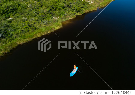 Happy mother with child have a fun on stand up paddle SUP board in sea lagoon. Healthy lifestyle. Recreational water sport, SUP tour in adventure camp on family summer beach vacation 127648445