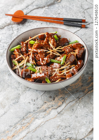 Ginger beef with crispy beef, a lightly sweet sauce, green onion and caramelized ginger closeup in the bowl. Vertical Ginger beef with crispy beef, a lightly sweet sauce, green onion and caramelized ginger closeup in the bowl. Vertical 127648610