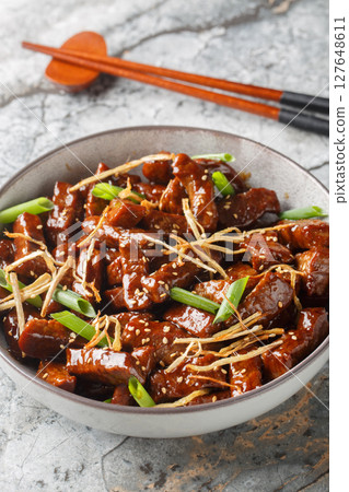 Ginger beef is a Canadian Chinese dish made from beef, ginger, and a distinctive sweet sauce closeup in the bowl. Vertical Ginger beef is a Canadian Chinese dish made from beef, ginger, and a distinctive sweet sauce closeup in the bowl. Vertical 127648611