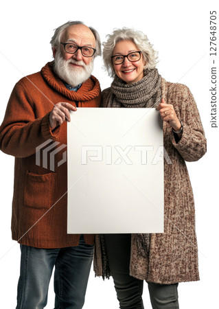 Elderly couple joyfully holding a blank canvas while standing together indoors in soft lighting 127648705