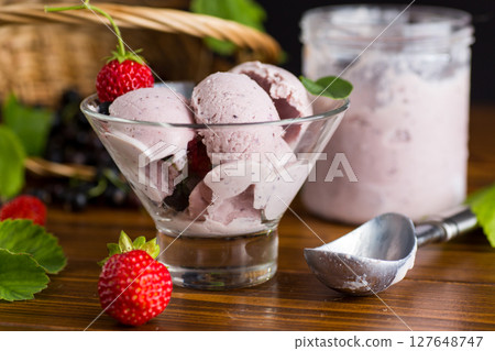 Blackcurrant ice cream with strawberries on wooden table Blackcurrant ice cream with strawberries on wooden table 127648747