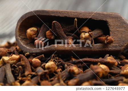 Dry cloves in wooden scoop isolated on wooden background with clipping path. Top view. Flat lay. selective focus. 127648977