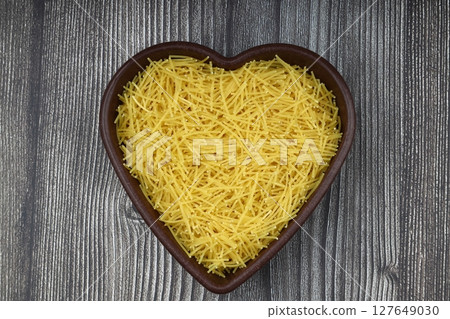 White gluten free vermicelli made from rice flour. Italian pasta in wooden spoon on dark textured background. Top view, space for text. 127649030