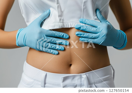 A doctor in blue gloves is closely examining a patient's abdomen, focusing on health and well-being during the check-up Generative AI 127650154