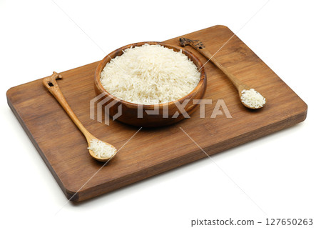 Raw white rice on wooden background. Long uncooked rice in wooden plate. Natural organic food. Traditional Asian cereal culture. Raw white rice on wooden background. Long uncooked rice in wooden plate. Natural organic food. Traditional Asian cereal culture. 127650263