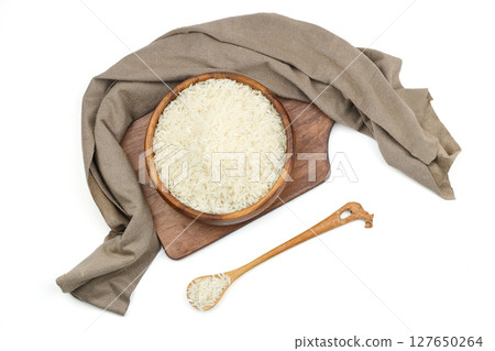 Raw white rice on wooden background. Long uncooked rice in wooden plate. Natural organic food. Traditional Asian cereal culture. 127650264