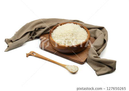 Raw white rice on wooden background. Long uncooked rice in wooden plate. Natural organic food. Traditional Asian cereal culture. Raw white rice on wooden background. Long uncooked rice in wooden plate. Natural organic food. Traditional Asian cereal culture. 127650265