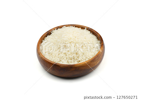 Raw white rice on wooden background. Long uncooked rice in wooden plate. Natural organic food. Traditional Asian cereal culture. 127650271