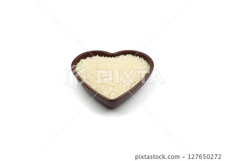 Raw white rice on wooden background. Long uncooked rice in wooden plate. Natural organic food. Traditional Asian cereal culture. 127650272