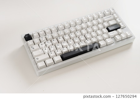 Modern mechanical keyboard on white desk as background. Minimal style and design keyboard. Custom build keyboard with black and white cap. Close up 127650294