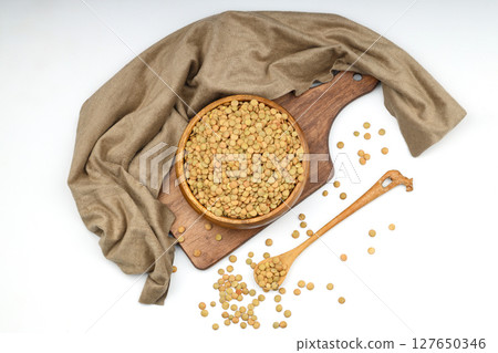 Green lentils in wooden bowl on isolated white background. Top view, copy space. Flat lay. Green lentils in wooden bowl on isolated white background. Top view, copy space. Flat lay. 127650346