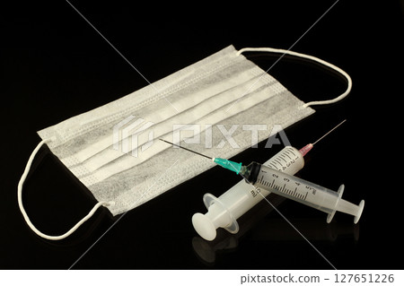 Medical mask and syringe on black background. The inscription covid on a black background 127651226