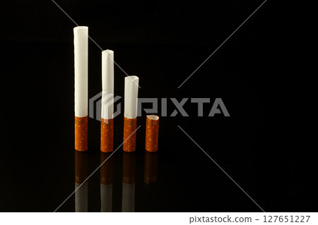 Nicotine addiction, a lot of cigarettes on a black isolated background Nicotine addiction, a lot of cigarettes on a black isolated background 127651227