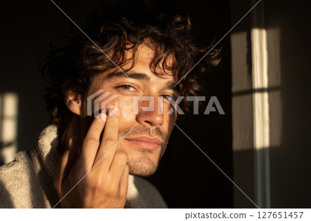 Man applying face cream during morning skincare routine 127651457