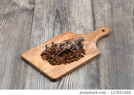 Dry cloves in wooden scoop isolated on wooden background with clipping path. Top view. Flat lay. selective focus. 127651488