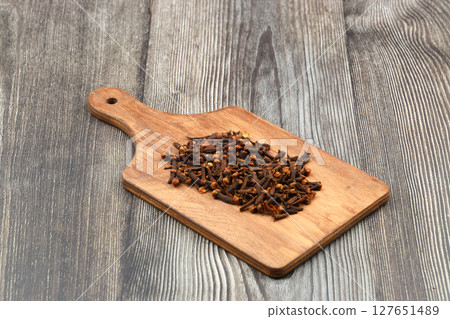 Dry cloves in wooden scoop isolated on wooden background with clipping path. Top view. Flat lay. selective focus. 127651489