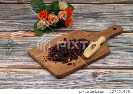 Karkade tea. Hibiscus tea leaves in wooden scoop isolated on wooden background. File contains clipping path. Top view. 127651496