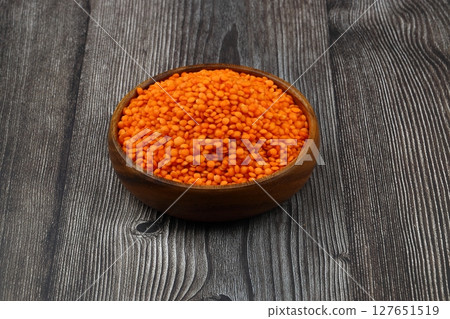Red lentils in wooden bowl on wooden table background. Top view, copy space. Flat lay. Red lentils in wooden bowl on wooden table background. Top view, copy space. Flat lay. 127651519