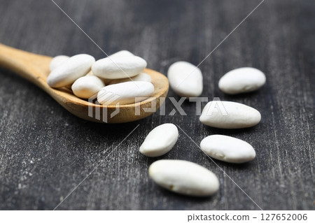 White Beans in a wooden spoon close-up on a wooden background. Vegetarian food. White Beans in a wooden spoon close-up on a wooden background. Vegetarian food. 127652006
