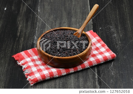 pile of black rice in a wooden bowl on a wooden table close-up 127652058