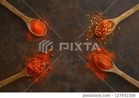 cayenne pepper on wooden spoon spices and dried chilli peppers background. group of red hot chilli powder on black plate 127652386