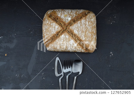 Sliced homemade sourdough rye bread with rye flour on black textured background. Top view or flat-lay. Low key 127652905