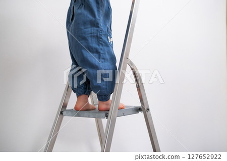 Tiny childs feet climbing a ladder, close up of little girl going up to help with painting 127652922