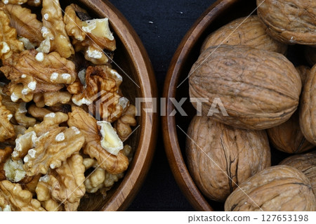 broken walnuts and nutcracker on black background 127653198