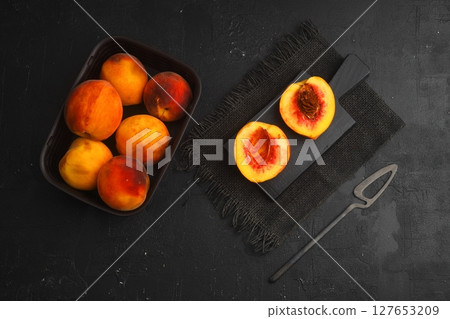 fresh juicy peaches with leaves on dark concrete background with knife 127653209