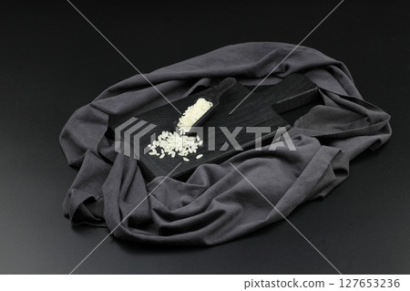 Raw white rice on black background. Long uncooked rice in wooden plate. Natural organic food. Traditional Asian cereal culture. 127653236