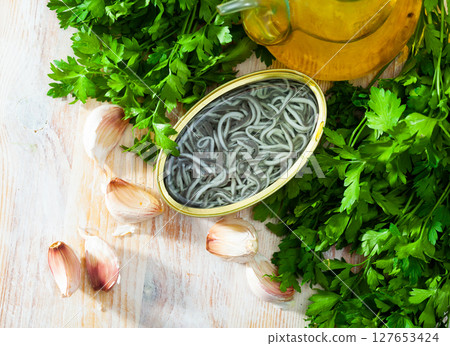 Pickled angoulas in tin can with garlic and parsley.  127653424