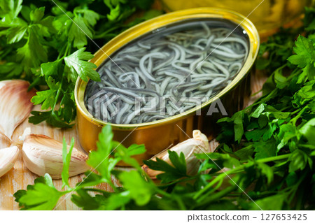 Pickled eels on background with garlic and greens at table Pickled eels on background with garlic and greens at table 127653425