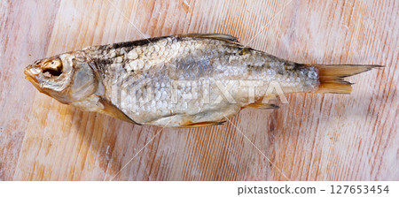 Dried salted fish on wooden background Dried salted fish on wooden background 127653454