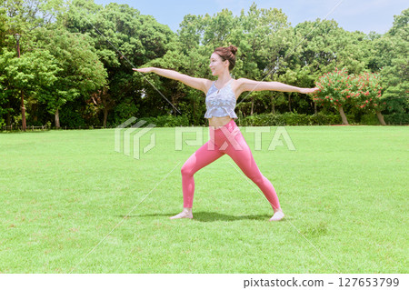 A woman doing yoga and pilates in a resort atmosphere under natural grass and blue skies A woman doing yoga and pilates in a resort atmosphere under natural grass and blue skies 127653799