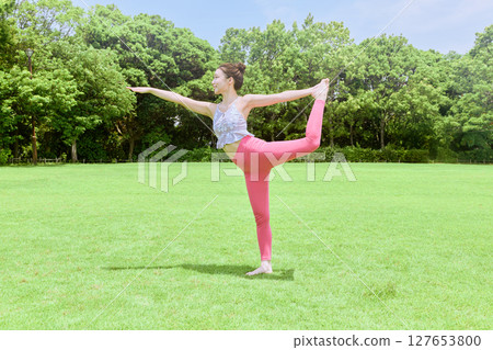 A woman doing yoga and pilates in a resort atmosphere under natural grass and blue skies A woman doing yoga and pilates in a resort atmosphere under natural grass and blue skies 127653800