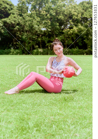 一位女士在天然草坪和藍天下，在度假氛圍中練習瑜伽和普拉提 127653831