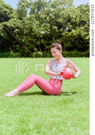 一位女士在天然草坪和藍天下，在度假氛圍中練習瑜伽和普拉提 127653832