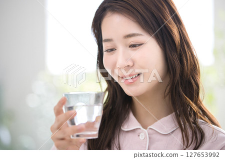 一名穿著睡衣的年輕女子醒來後喝水 127653992