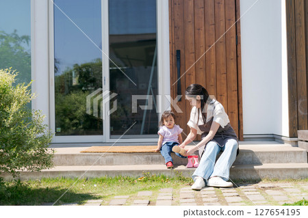 A mother putting shoes on her child A mother putting shoes on her child 127654195