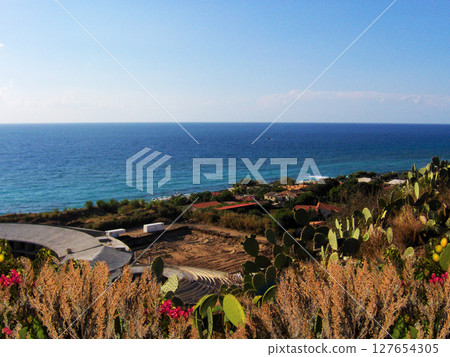 A breathtaking view unfolds along the Calabrian coast, where the crystal-clear blue sea meets the lush, vibrant Mediterranean vegetation. From the cliffs and winding roads. 127654305