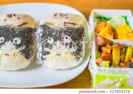 A cat-shaped rice ball bento wrapped in plastic wrap 127654758