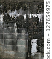 A concrete wall covered with mold, giving off a Showa-era vibe. Background material. Gloomy. 127654975